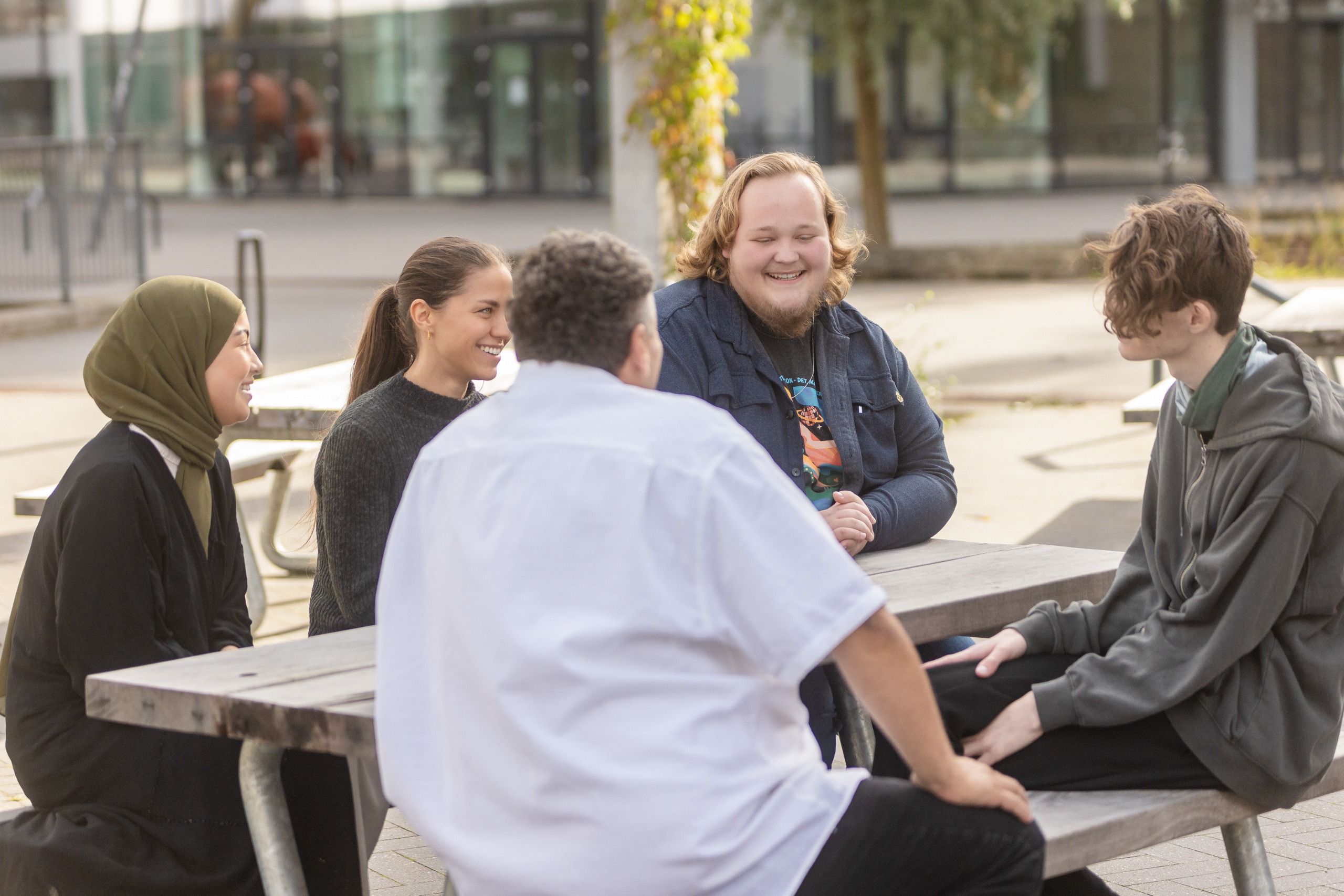 kursister og elever hygger uden for ved bænk